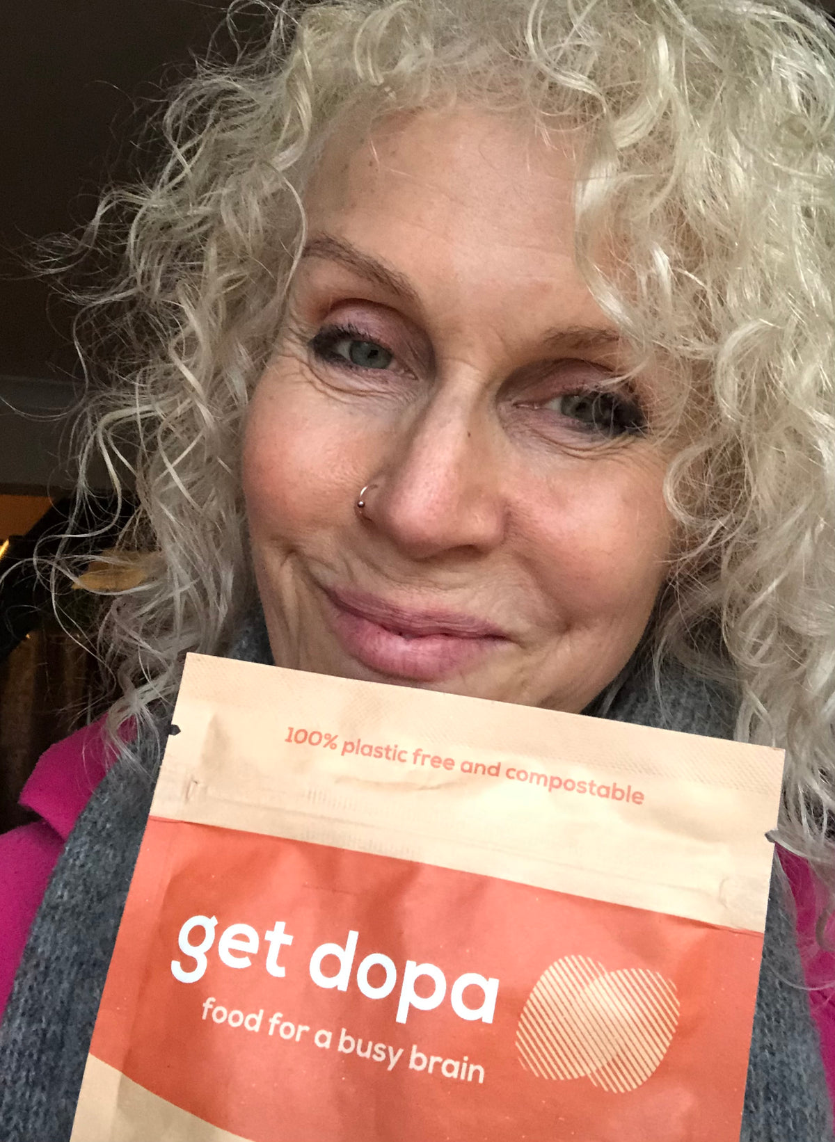 Person holding a 'get dopa' package with a neutral background