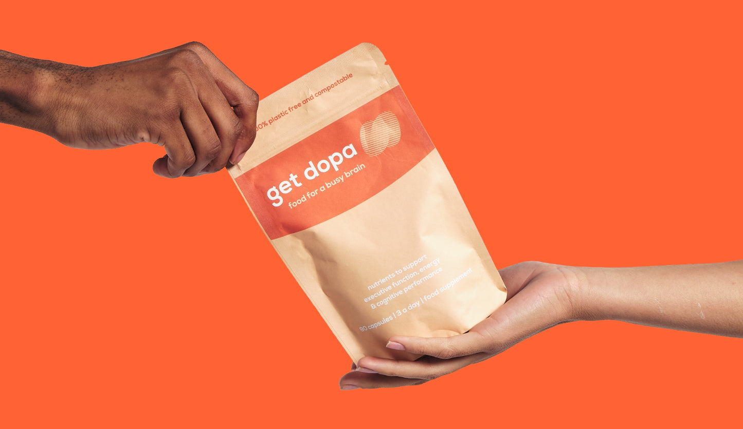 Hand holding a 'get dopa' package against an orange background